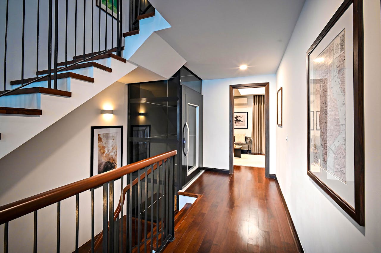 Sleek and modern corridor with staircase featuring wooden floors and stylish railing.