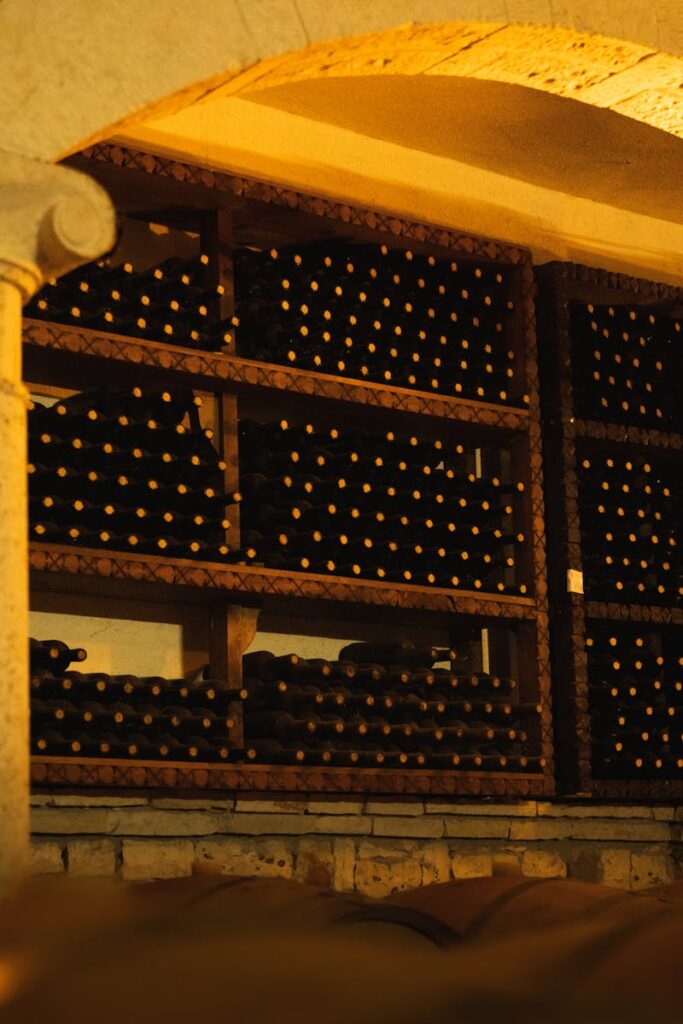 A rustic wine cellar with shelves of aged wine bottles under warm lighting.