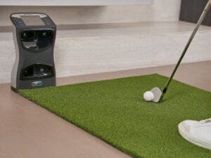 Golf putting practice on artificial turf with a training aid indoors.